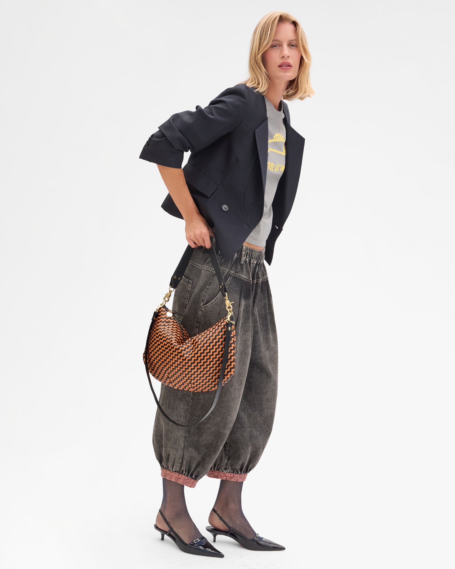 Model carrying the Black/ Natural Woven Zig-Zag Moyen Messenger by the shoulder strap.
