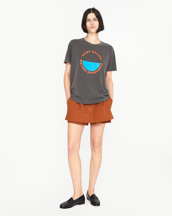 athena wearing a rust color skort with her hands in its pockets with the  original tee faded black with bright poppy st calais blue maison bourgneuf and black loafers
