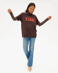 Maly taking a step wearing the Cocoa Ciao Original Tee over jeans