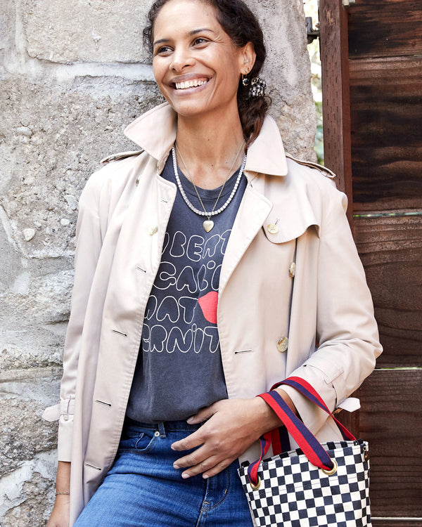 Model wearing the Faded Black Liberte Egalite Maternite Original Tee with a trench coat over it 