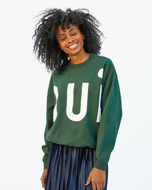 Mecca wearing the Forest Grand Oui Oversized Sweatshirt with a pleated blue skirt