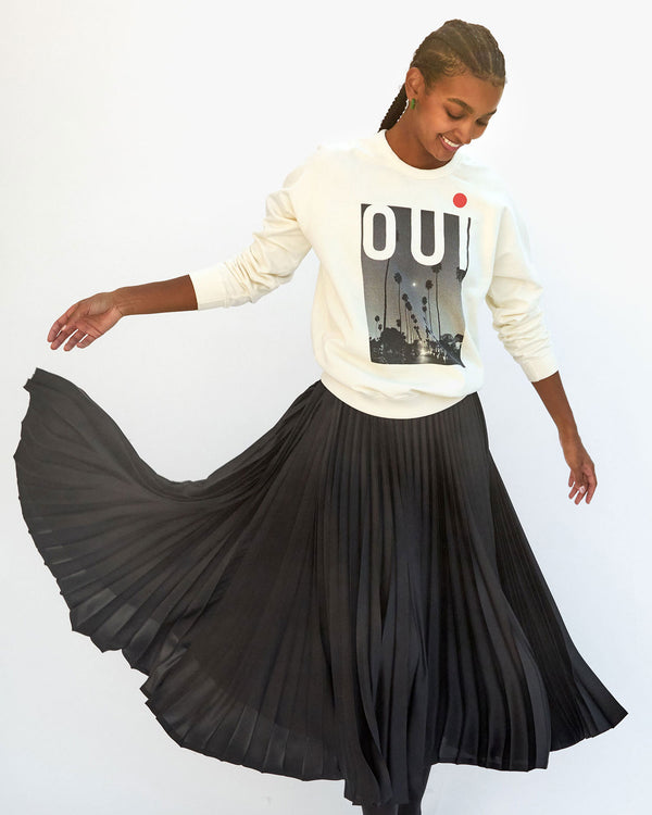 Jordan wearing the cream oui oversized sweatshirt with a black pleated skirt 