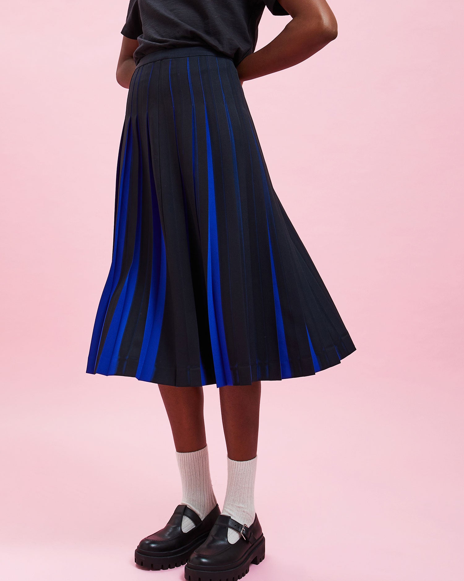 Model wearing the Navy & Black Stripes w/ French Blue Pleats Pleated Skirt with a black tee shirt tucked in 