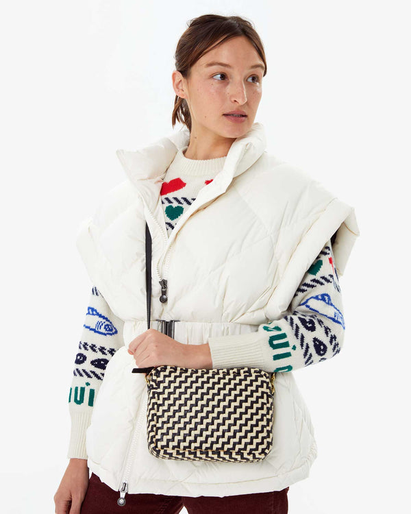 Zoe wearing the Pryenex Diana Vest in Milk over the CV Icon Sweater. she has the black and cream woven zig zag midi sac on