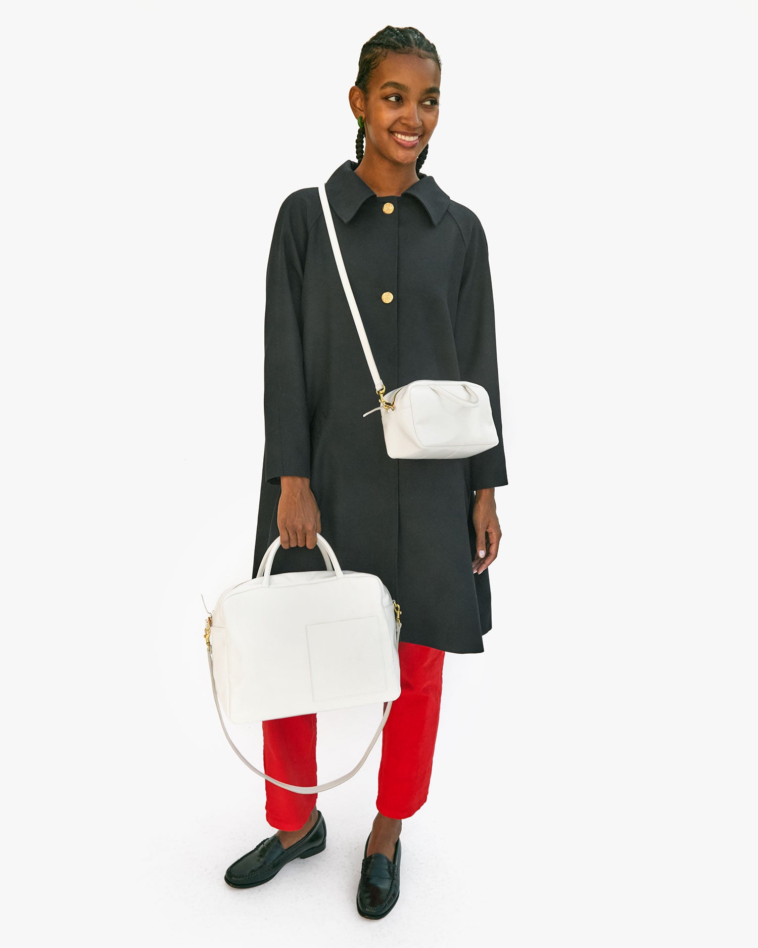 Jordan wearing the Brie Petit Claude crossbody and holding the Brie Claude by its top handle