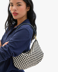 Sandra wears the Black & Cream Woven Checker Petit Moyen Messenger on her shoulder