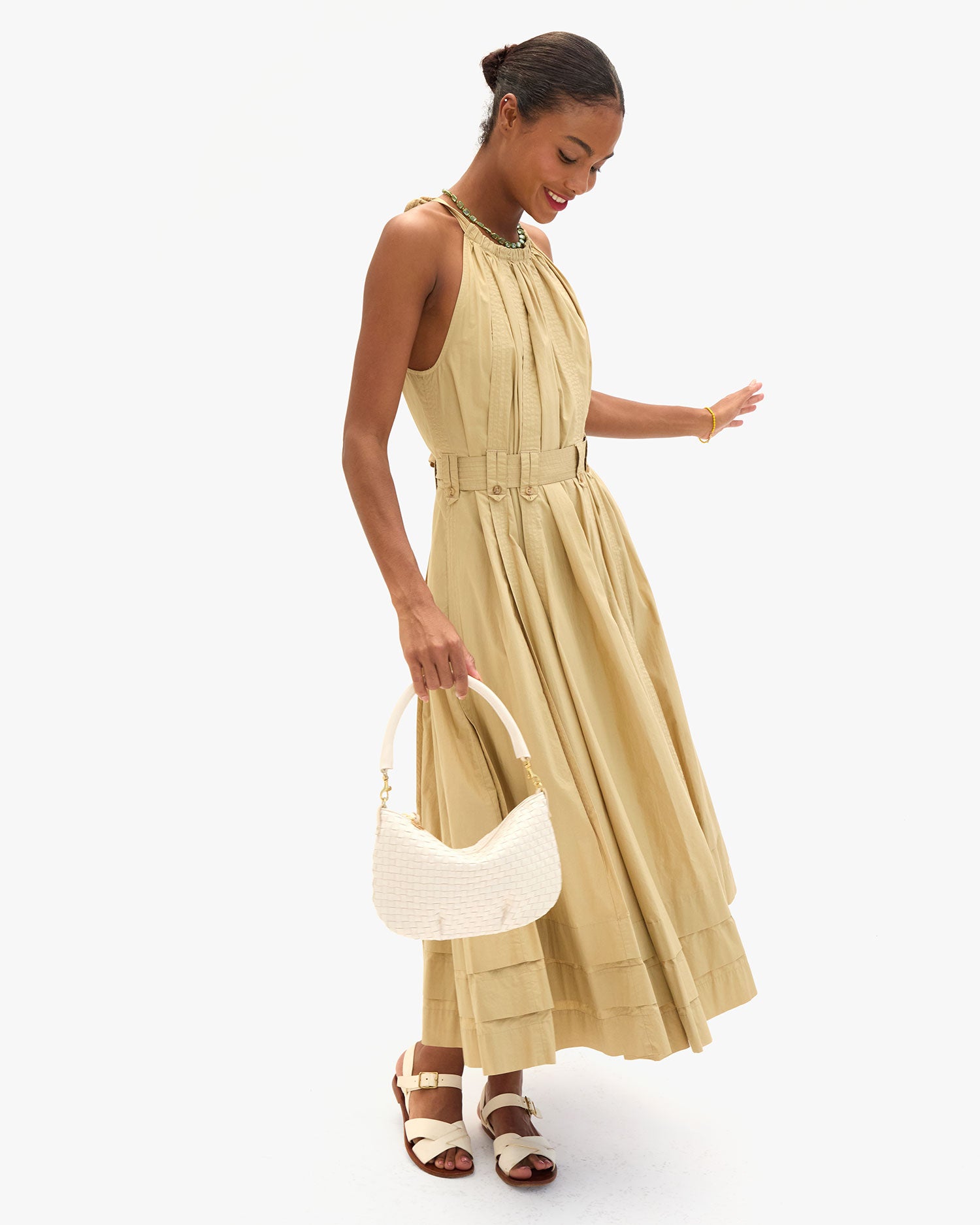 Model wearing a tan dress and carrying the Cream Woven Checker Petit Moyen as a top handle bag via the Shoulder Strap. 