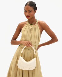 Model carrying the Cream Woven Checker Moyen Messenger as a top handle bag.