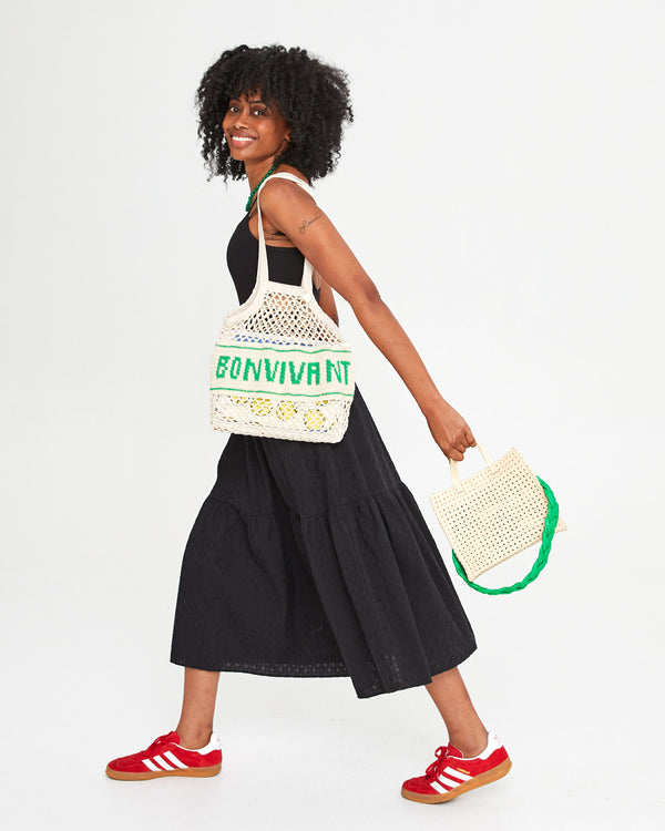 Mecca carrying the Natural with Bon Vivant Woven Netty on her shoulder. she's also holding the cream rattan petit simple tote with the parrot braided leather shoulder strap