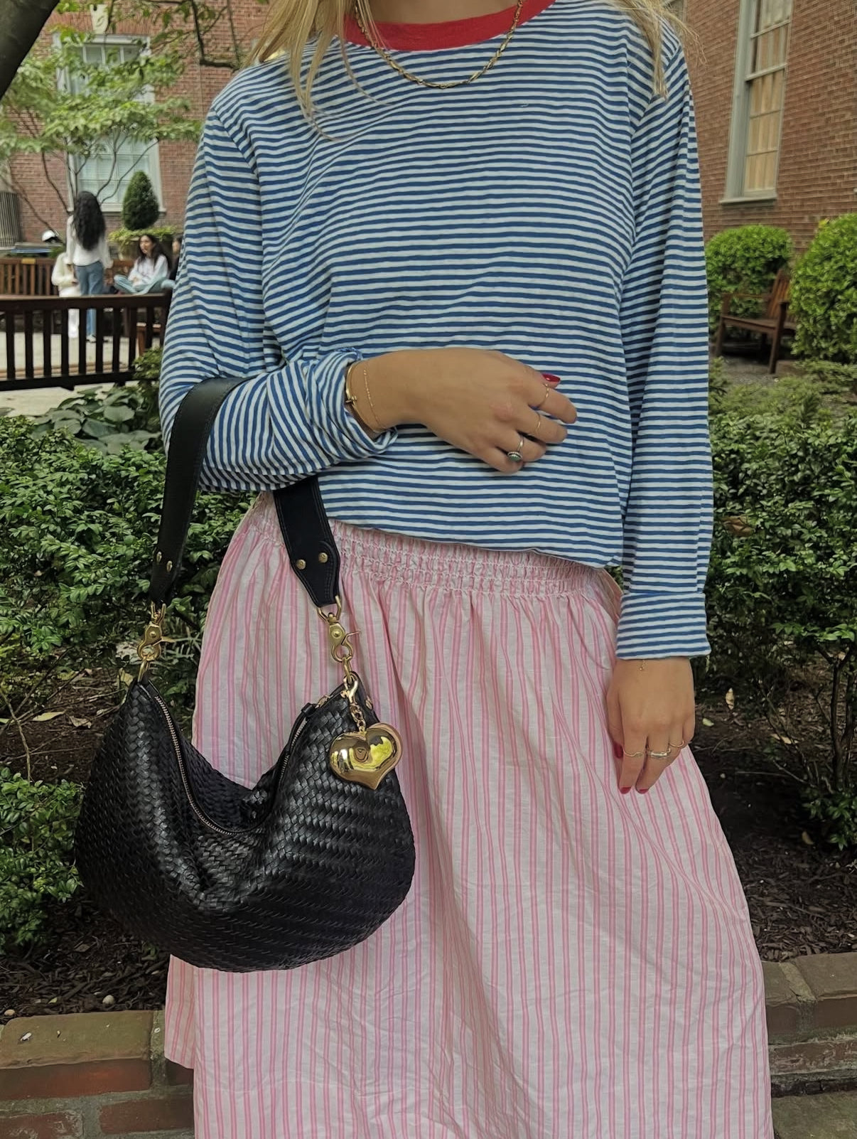 Woman carrying the Black Woven Zig Zag Moyen Messenger with Grande Mylar Heart Fob. 