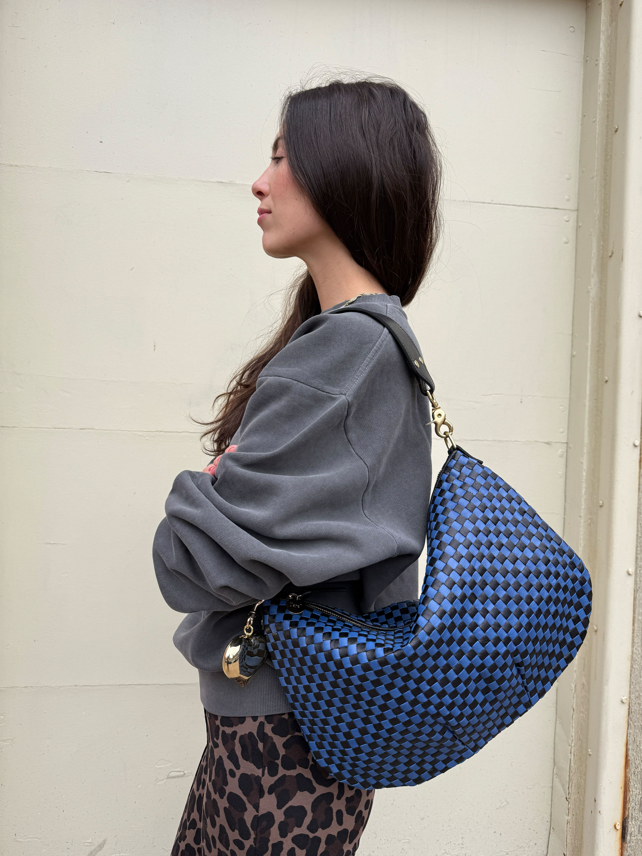 Woman carrying the Black and Cobalt Checker Moyen Messenger. 