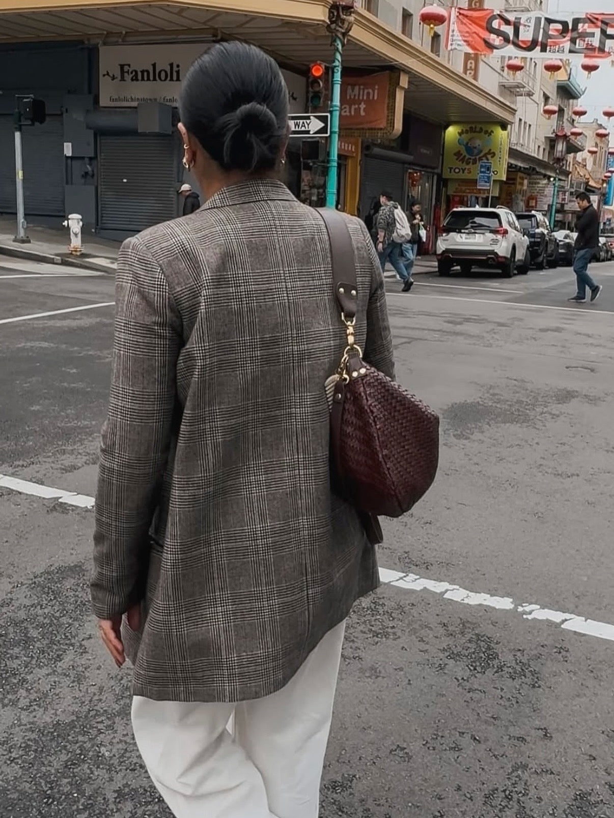 Woman wearing a Blazer with White Pants and carrying a Moyen Messenger. 