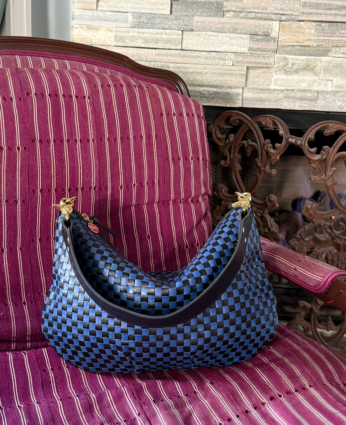 Black and Cobalt Moyen Messenger on top of a burgundy chair. 