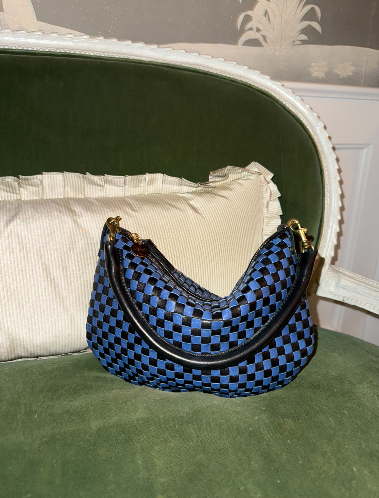 Black and Cobalt Checker Petit Moyen sitting on an olive colored velvet chair. 