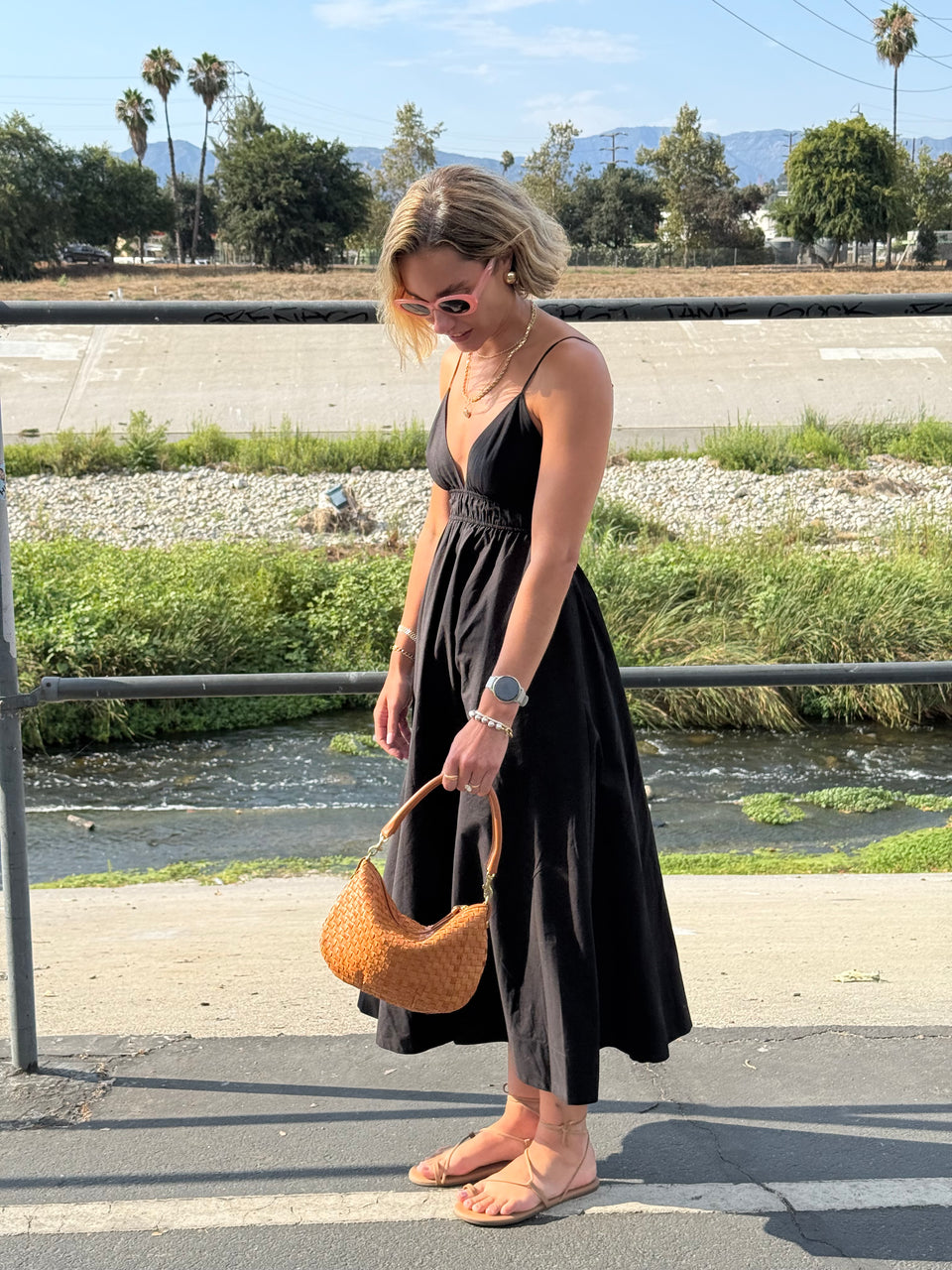 Woman wearing a black dress as she's holding onto her Natural Woven Petit Moyen. 