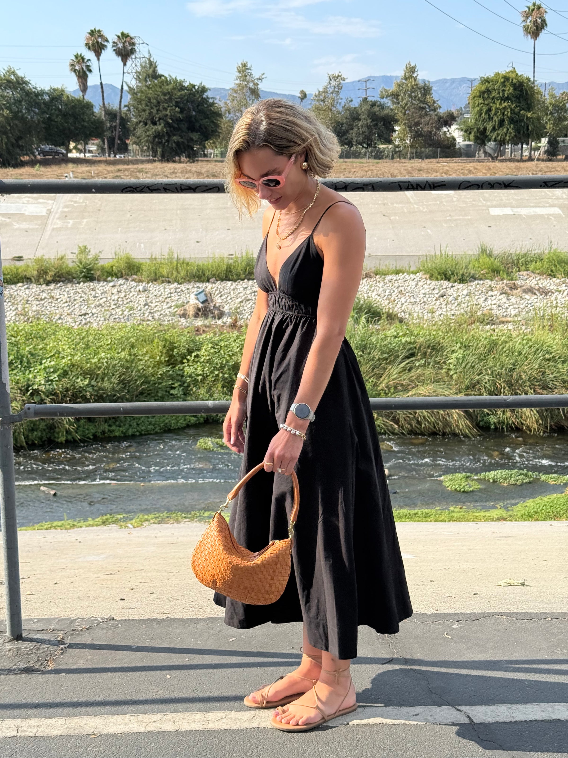 Woman wearing a black dress as she's holding onto her Natural Woven Petit Moyen. 