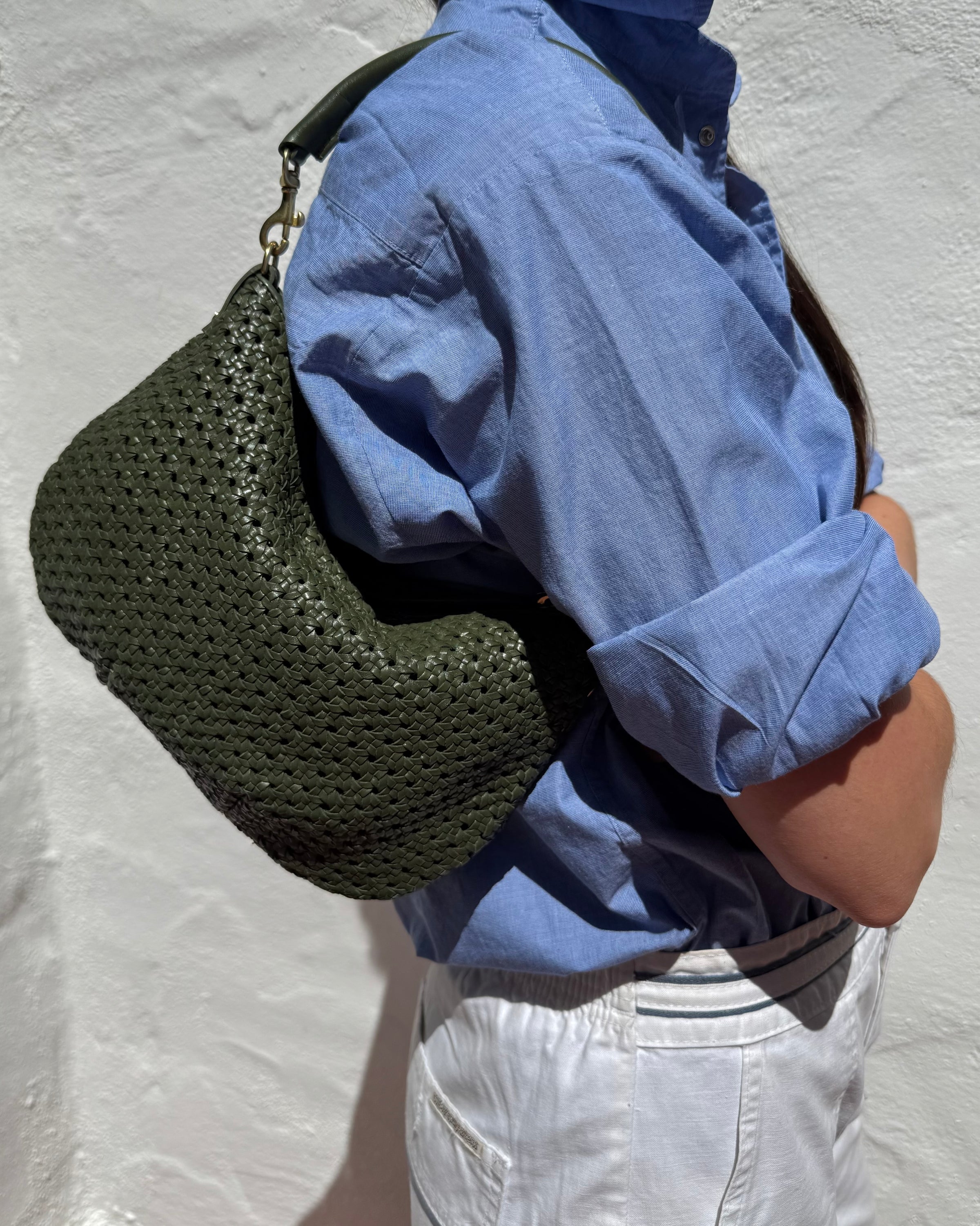 Close-up of a person carrying the Army Rattan Petit Moyen as a shoulder bag. 