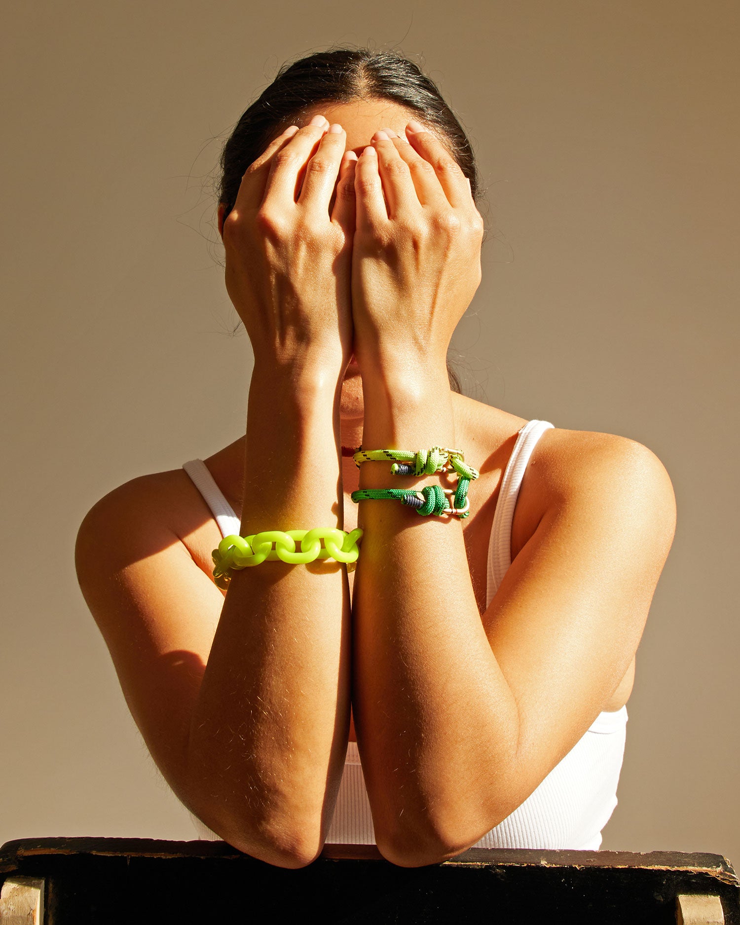 Andrea with her hands covering her face. she's wearing the yellow and green Sailcord Bracelets and the neon yellow resin bracelet.