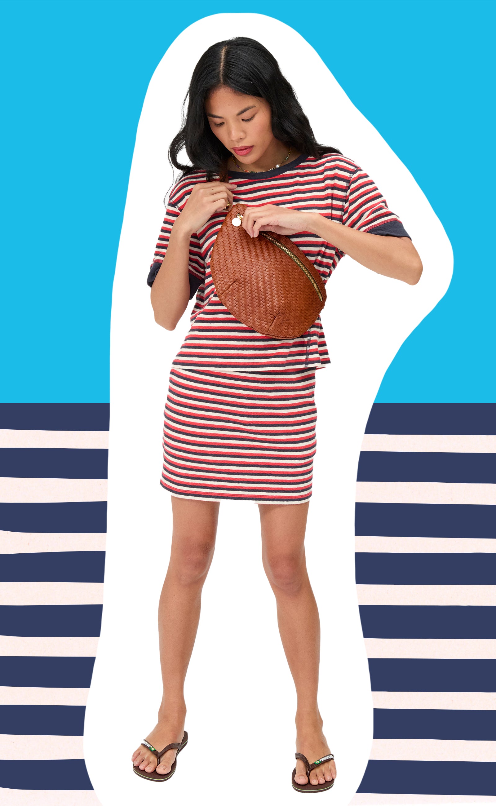 Model carrying the Hazelnut Grande Fanny and wearing the Navy, Cherry, and Cream Stripe Le Bateau Tee and Le Mini Tube Skirt.