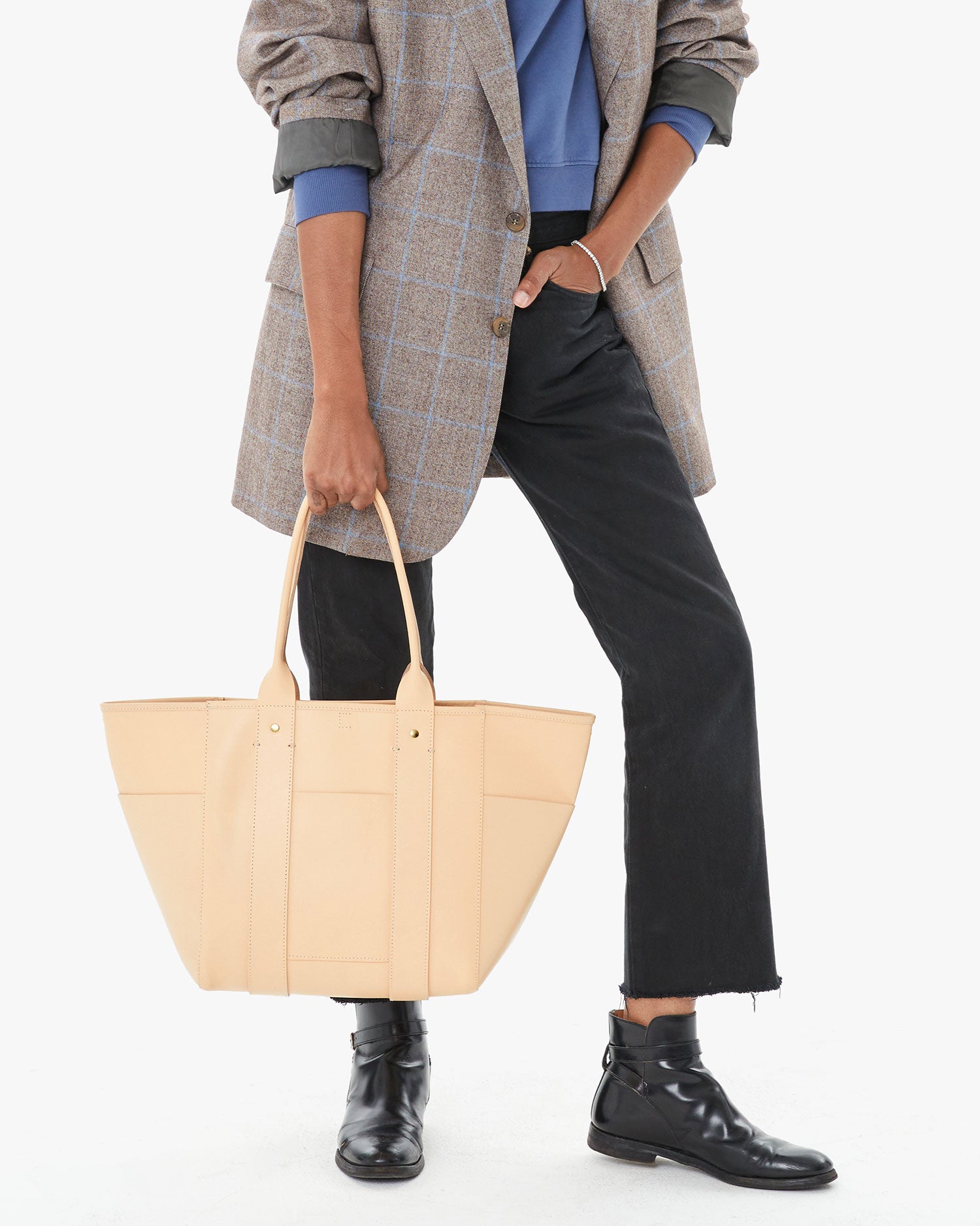 Mecca holding the Undyed Veg Le Slim Box Tote in her right hand
