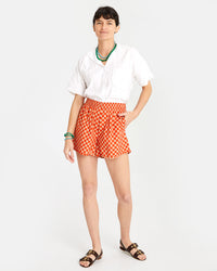 Danica wearing the Poppy & Khaki Checker St. Martin Shorts with a white blouse tucked in. she has on some green and blue accessories and black sandals