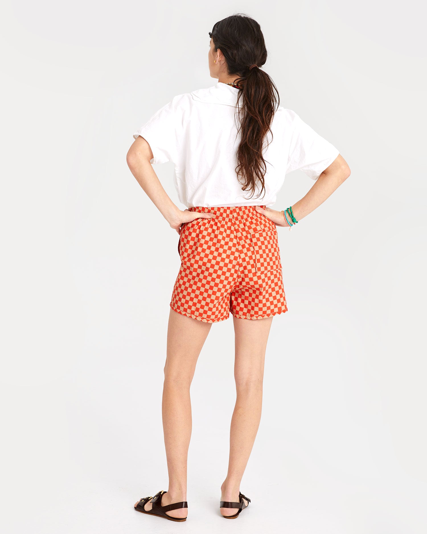 back view of danica in the Poppy & Khaki Checker St. Martin Shorts with  her white blouse tucked in 