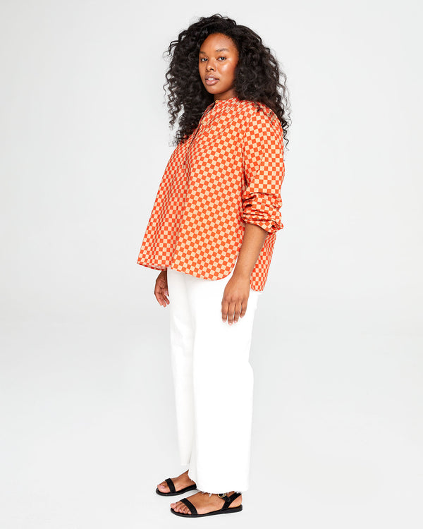 candice looking at the camera wearing the Poppy & Khaki Checker St. Martin Top with wide leg white pants and black sandals
