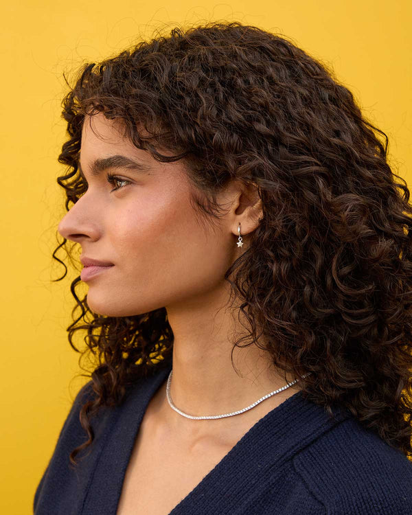 Haro wearing the Sterling Silver Star Mini Hoop with her hair tucked behind her ear