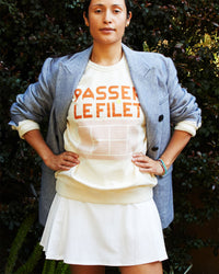 Andrea wearing the Sweatshirt in Cream w/ Passer le Filet with a white tennis skirt