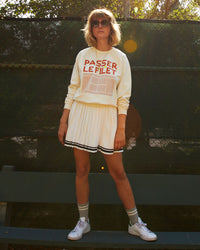 Lou wearing the Sweatshirt in Cream w/ Passer le Filet with a white tennis skirt