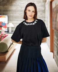Zoe wearing the Black w/ Cream Charmant Tee  tucked in to the pleated skirt 