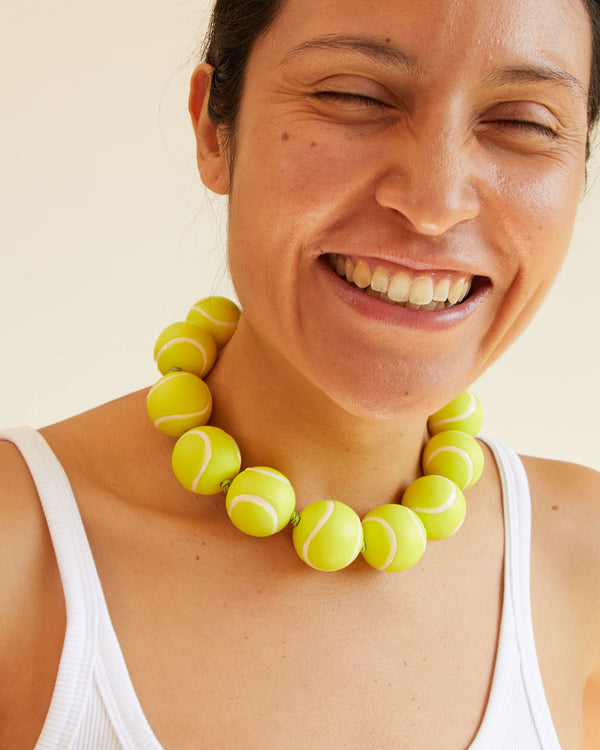 Andrea smiling and wearing the Neon Yellow Tennis Ball Collar with a white tank top 