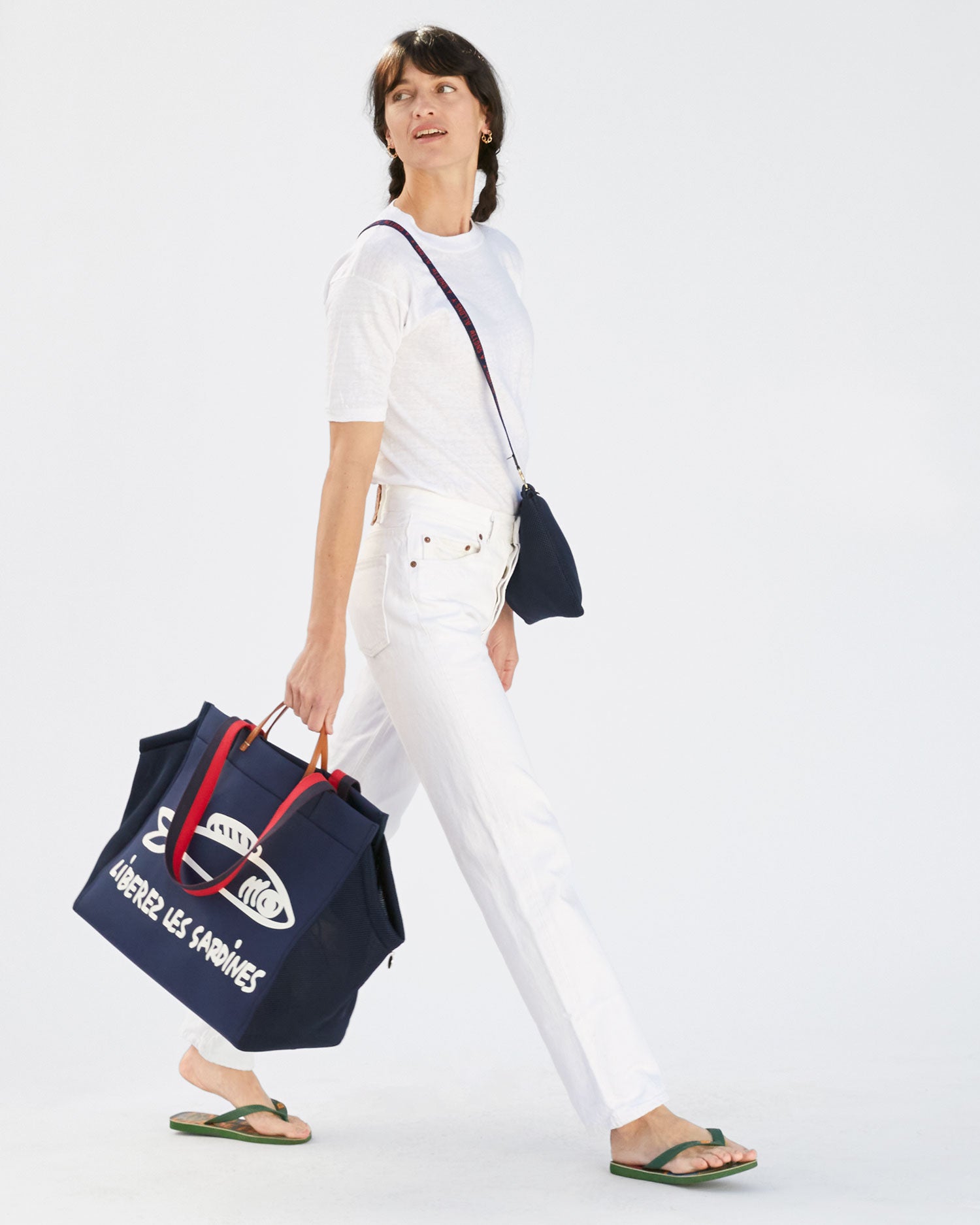 Danica wearing all white and carrying the Navy Liberez Les Sardines Trucker Beach Tote via the top handles. 