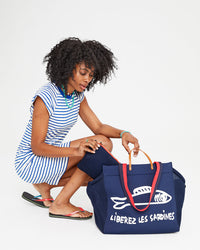Mecca wearing the Cobalt and Cream Petit Stripe Raglan Tank Dress and  inserting the Navy Flat Clutch with Tabs inside of the Navy Liberez Les Sardines Trucker Beach Tote.