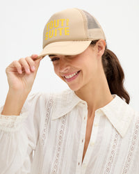 Woman wearing the cream Amélie Blouse and 'Tout de Suite' Trucker Hat. 