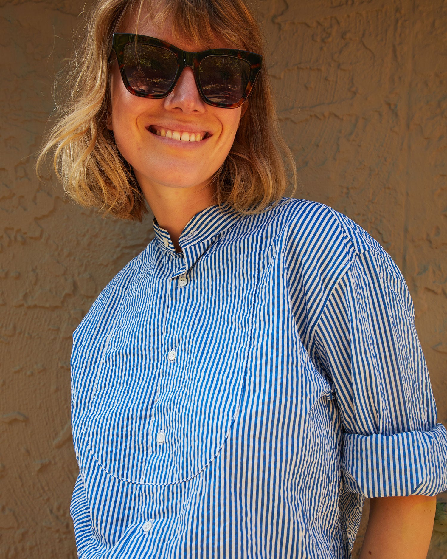 Lou smiling and wearing the Steven Alan Tux Shirt In Blue and Cream Stripe with the sleeves rolled up