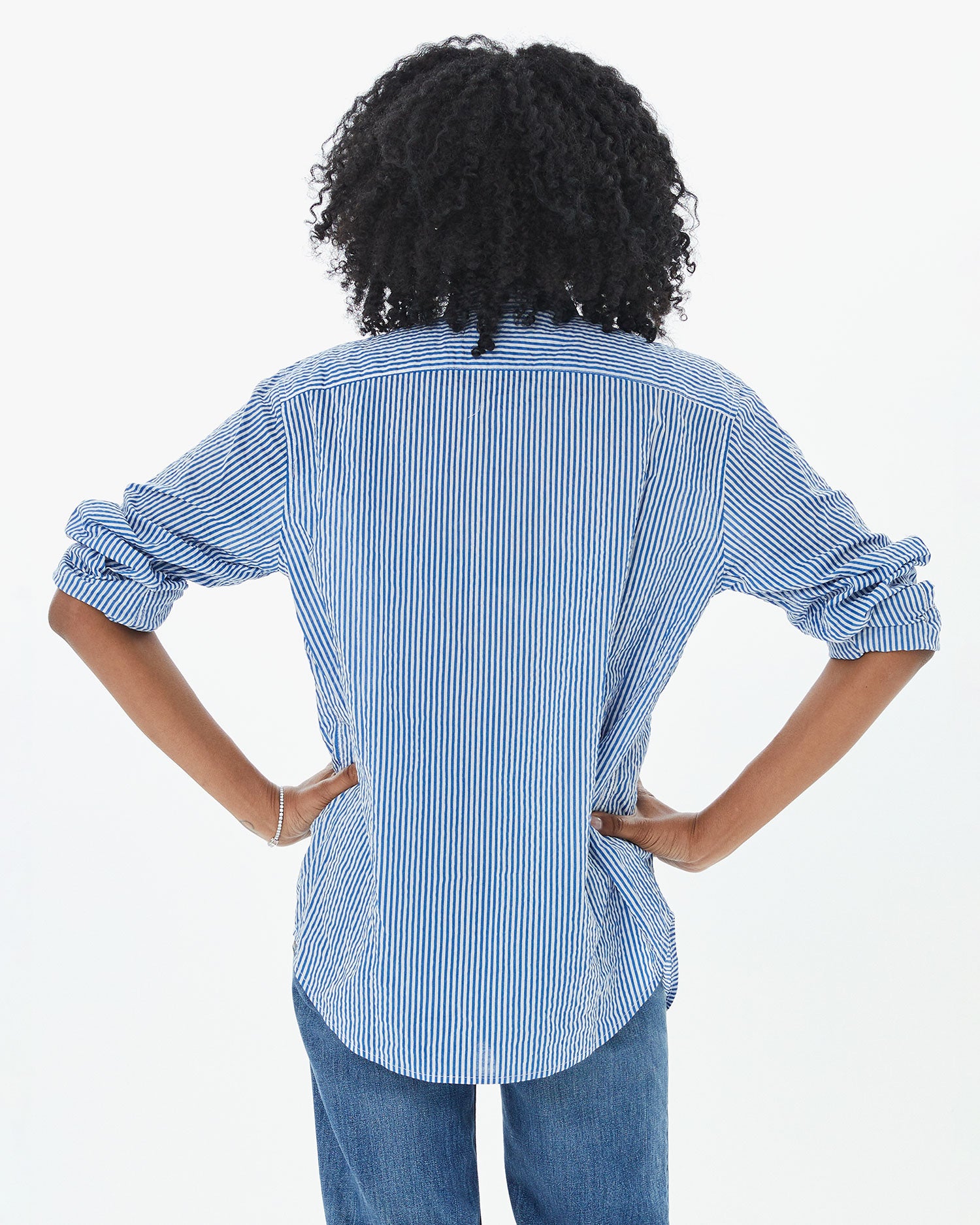 back view of Mecca in the Steven Alan Tux Shirt In Blue and Cream Stripe with her hands on her hips