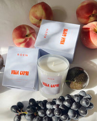 Roen Candle in the scent Villa Capri next to the candle box and some fruit