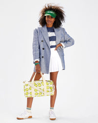 Mecca wearing a striped tshirt, a white tennis skirt, a blazer, the allons-y visor. she's carrying the Natural w/ Tennis Balls Duffle with the cream braided shoulder strap