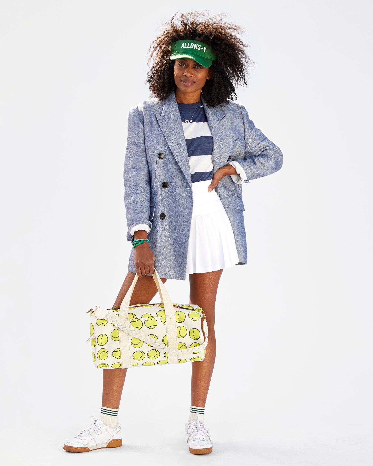 Mecca wearing a striped tshirt, a white tennis skirt, a blazer, the allons-y visor. she's carrying the Natural w/ Tennis Balls Duffle with the cream braided shoulder strap