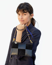 Danica holding the Black Suede & Nappa Wallet Clutch with Tabs by the royal blue grosgrain chain strap