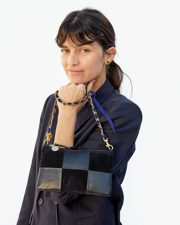 Danica holding the black suede and nappa wallet clutch with tabs by the Royal Blue Grosgrain Chain Shoulder Strap 