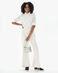 Mecca wearing the Cream Heart Coupé Anette Tuxedo Shirt tucked into white slacks