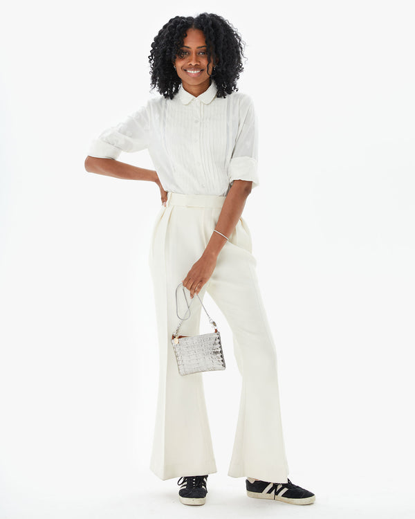 Mecca wearing the Cream Heart Coupé Anette Tuxedo Shirt tucked into white slacks