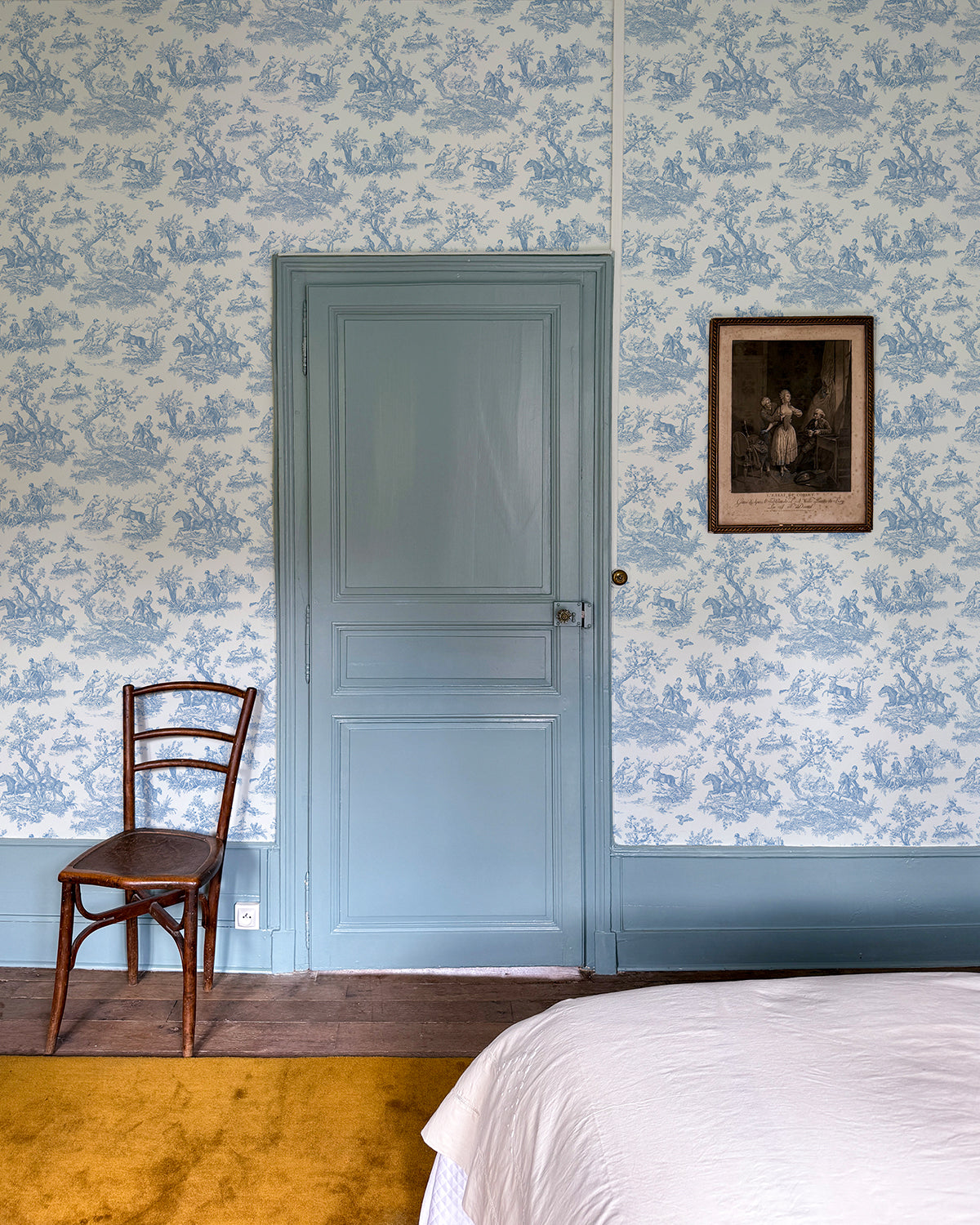 Room with a blue door and trimming and the Blue 'Toile du Saint Calais' wallpaper.