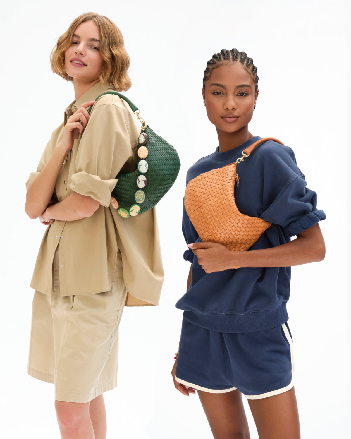 Two models carrying the Petit Moyen as a shoulder bag. One is carrying the Evergreen Woven Petit Moyen with Multi Cameo Shortie Strap. The other model is wearing the Navy Oversized Short Sleeve Sweatshirt with matching Le Jogging Shorts and carrying the Natural Woven Checker Petit Moyen. 
