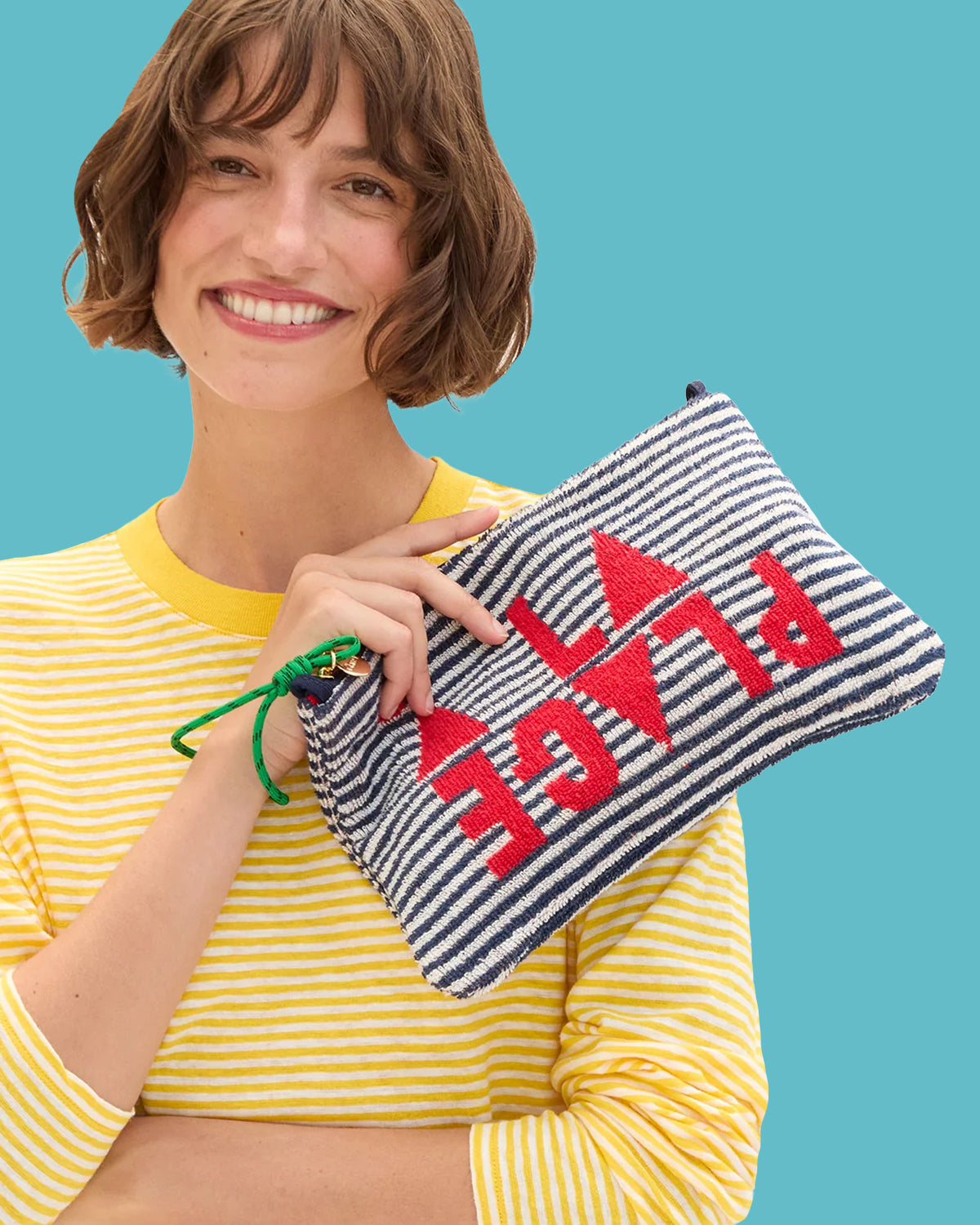 Model wearing the Snapdragon and Cream Mini Stripe Long Sleeve Tee and holding the À la Plage Flat Clutch with Tabs.