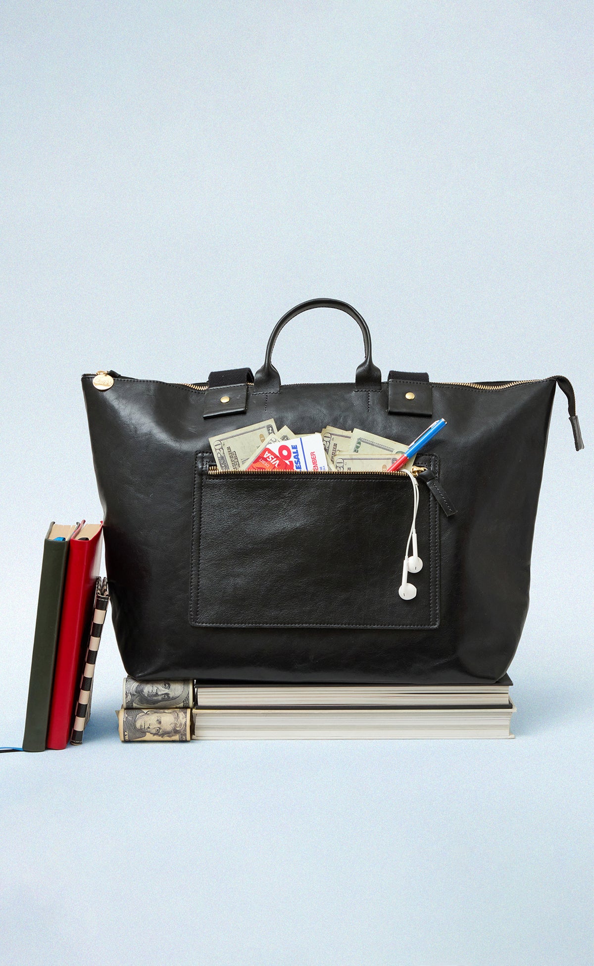 Black Le Zip Sac with exterior pocket unzipped with cash and cards sticking out.