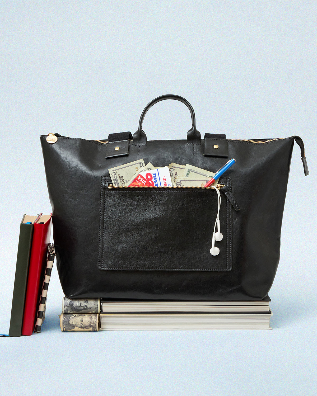 Black Le Zip Sac with exterior pocket unzipped with cash and cards sticking out.