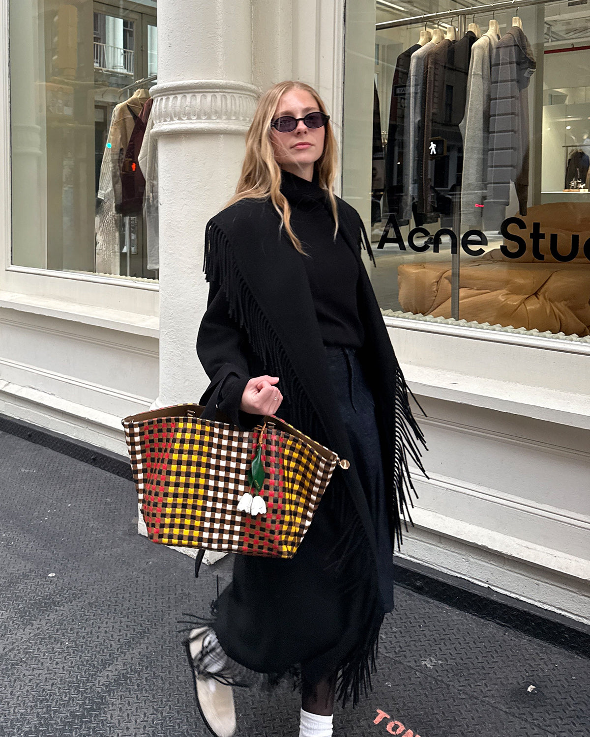 Woman carrying the Harlequin Woven Checker Bateau Tote with La Fleur Fob. 
